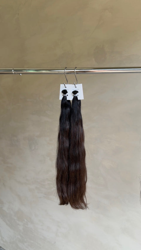 bundles of dark brown to black wavy hair extensions Wavy brown Slavic hair extensions with seamless keratin bonds at a North Lakes hair salon in North Brisbane