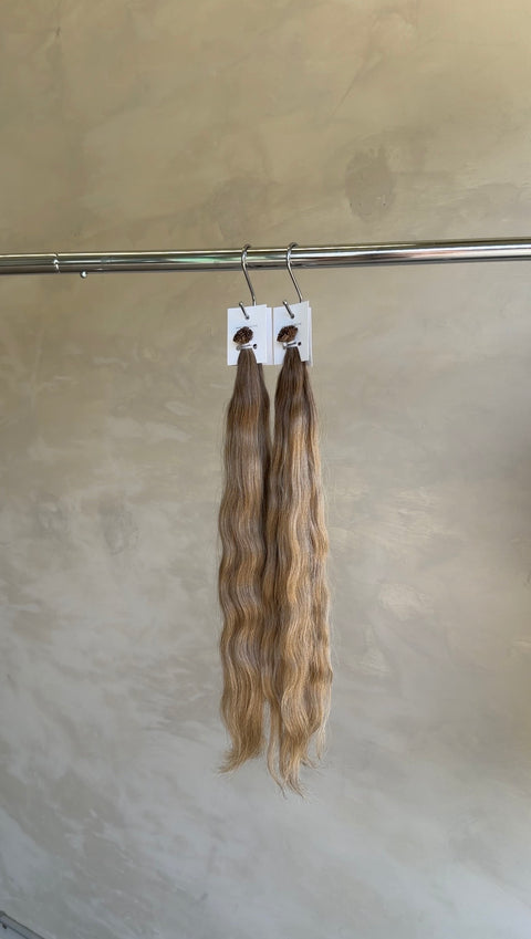 Long blonde Slavic keratin bond extensions with a beautiful flowing wave, adding natural-looking length, volume and texture in North Lakes, North Brisbane